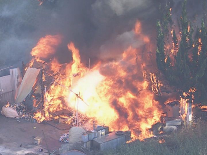 消防隊員のすぐ近くでも炎噴き出す…木造の小屋がほぼ全焼する火事 近くの廃材にも燃え移る